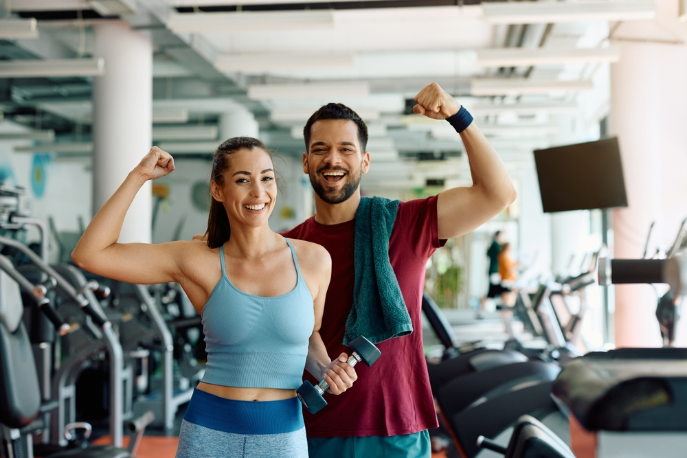 Fit couple proudly showcasing their muscle tone after a gym session, embodying the combined benefits of regular workouts and Fascial Stretch Therapy.