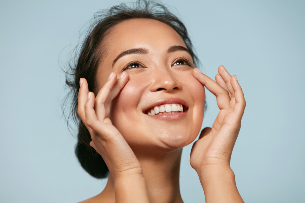 Radiant Skin from Red Light Therapy. Close-up of a smiling Asian woman with healthy skin, highlighting the rejuvenating effects of Red Light Therapy.